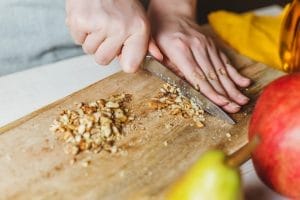 Chopping walnuts on wooden board with knife.