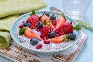 Chia pudding with fresh berries on wooden tray.