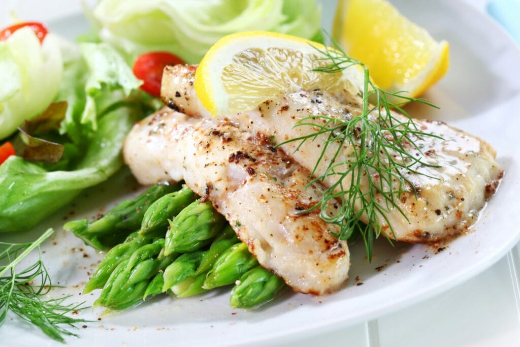 pollock cooked on a white plate, with lemon instead of lie.